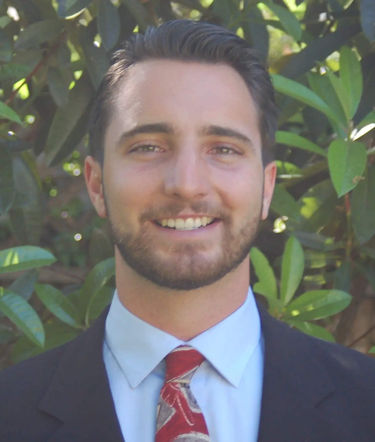 Image of owner Austin Clarence in suit similing.